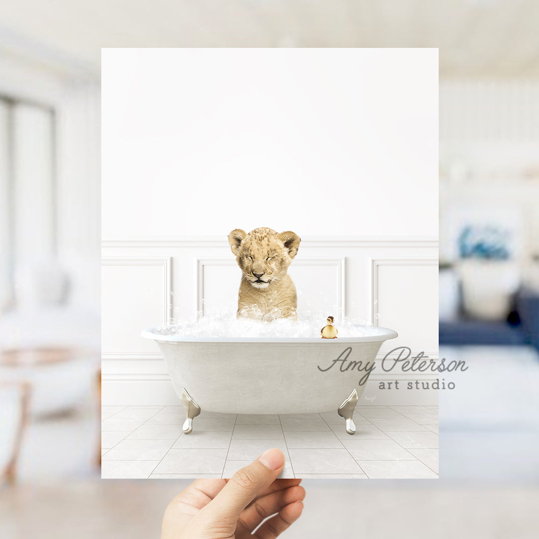 a hand holding a photo of a lion cub in a bathtub