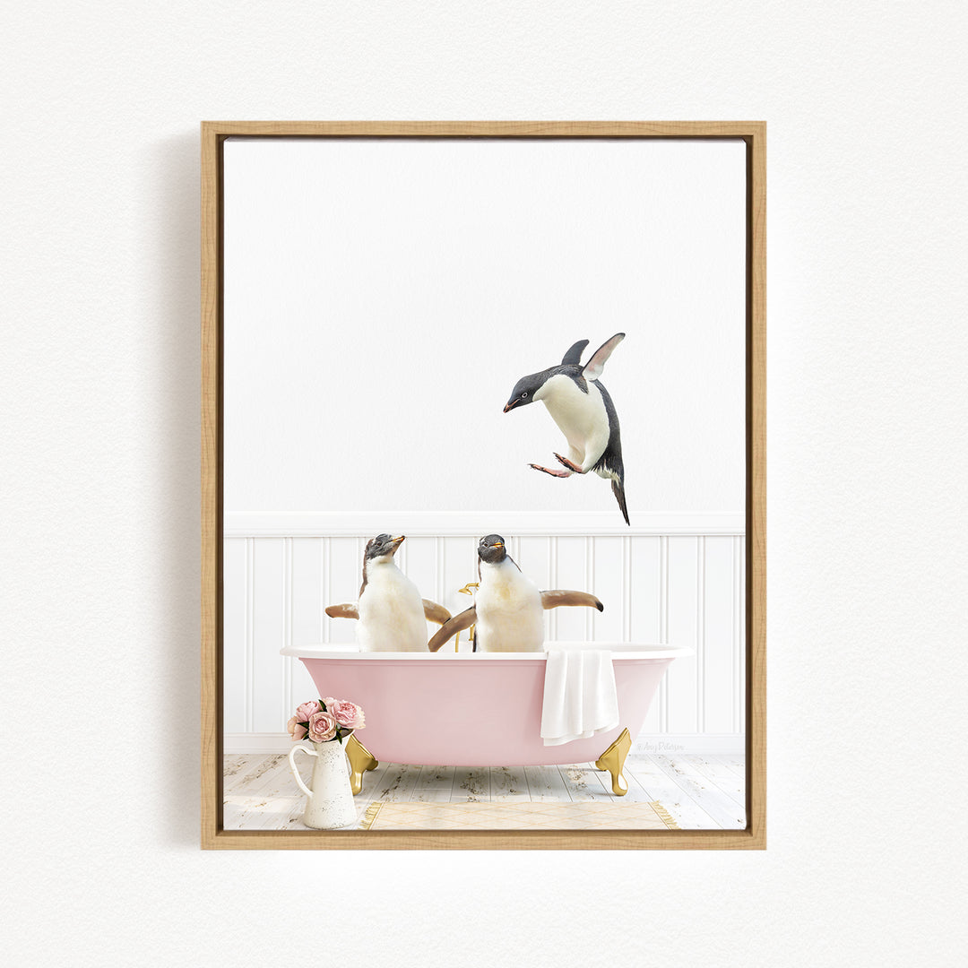 A framed image depicting three penguins sitting in a pink bathtub, with one penguin flying towards the tub.