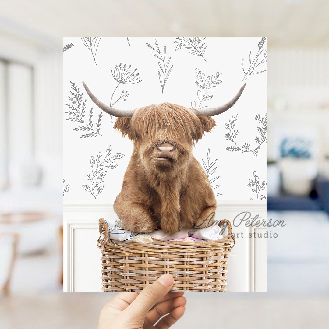 a hand holding up a card with a picture of a highland cow in a basket