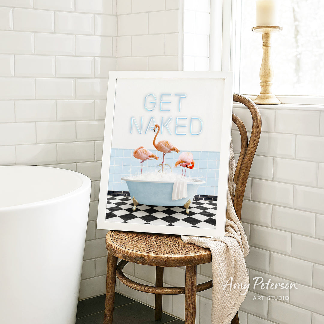 a framed print of a bathroom scene with a bathtub, a towel, and three flamingos.