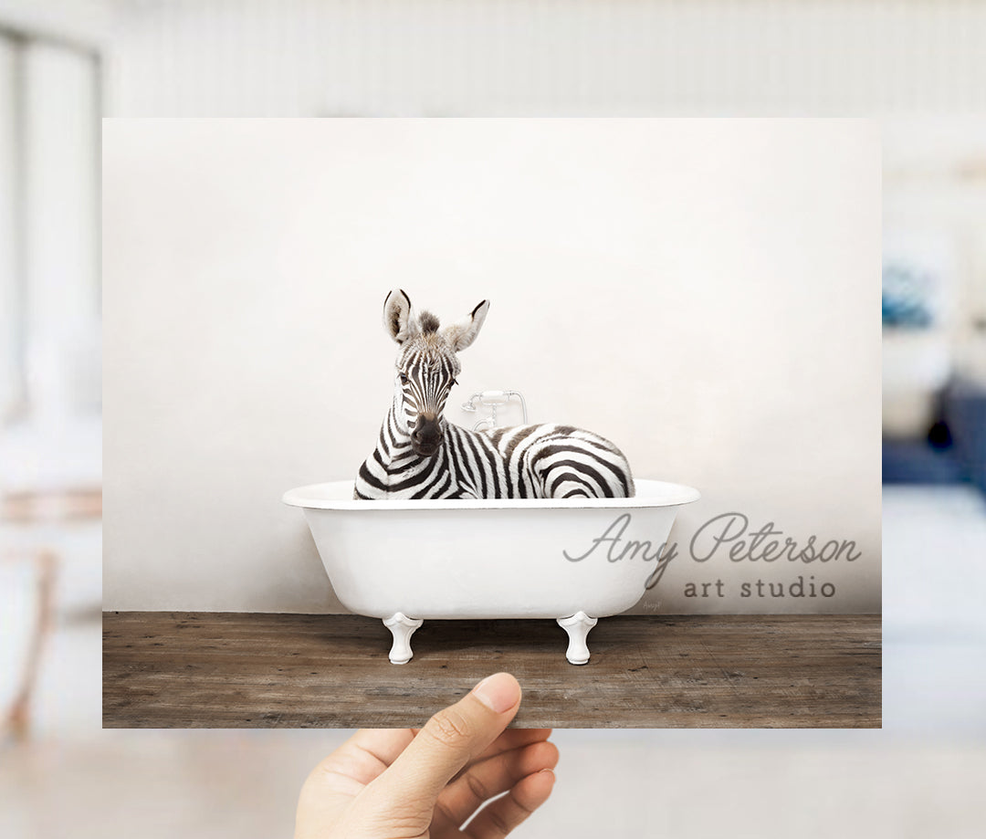 a hand holding up a card with a zebra in a bathtub