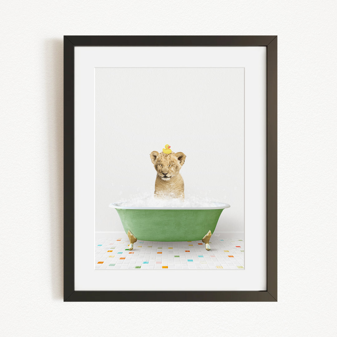 A young lion cub sitting in a green bathtub filled with water, with a yellow rubber duck floating on the water.