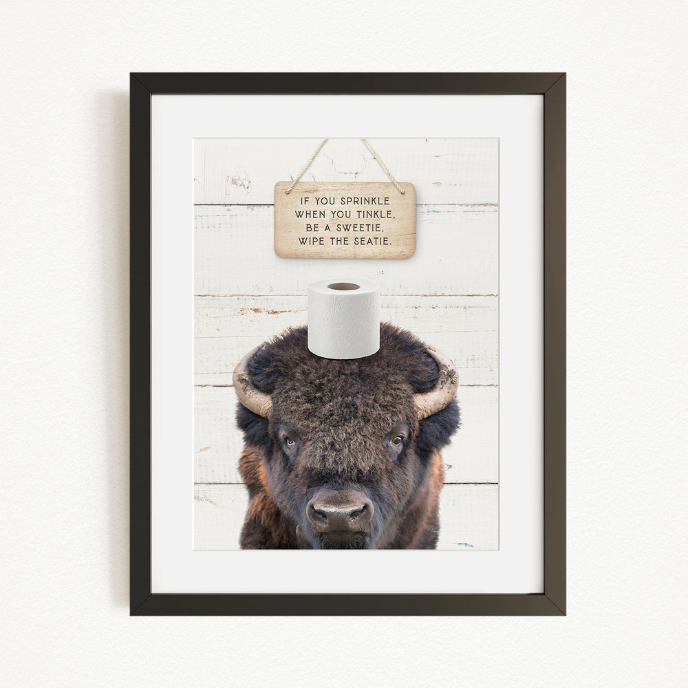 A framed image of a bison with a sign above it that reads "If you sprinkle when you tinkle, wipe the seagrass".