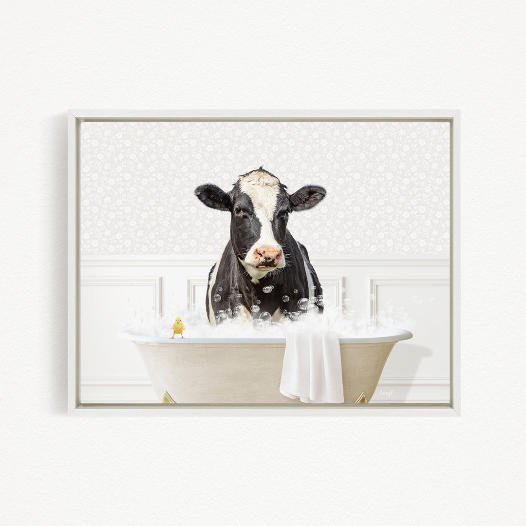 A black and white cow is sitting in a bathtub filled with bubbles, with a small yellow bird perched on the edge of the tub.