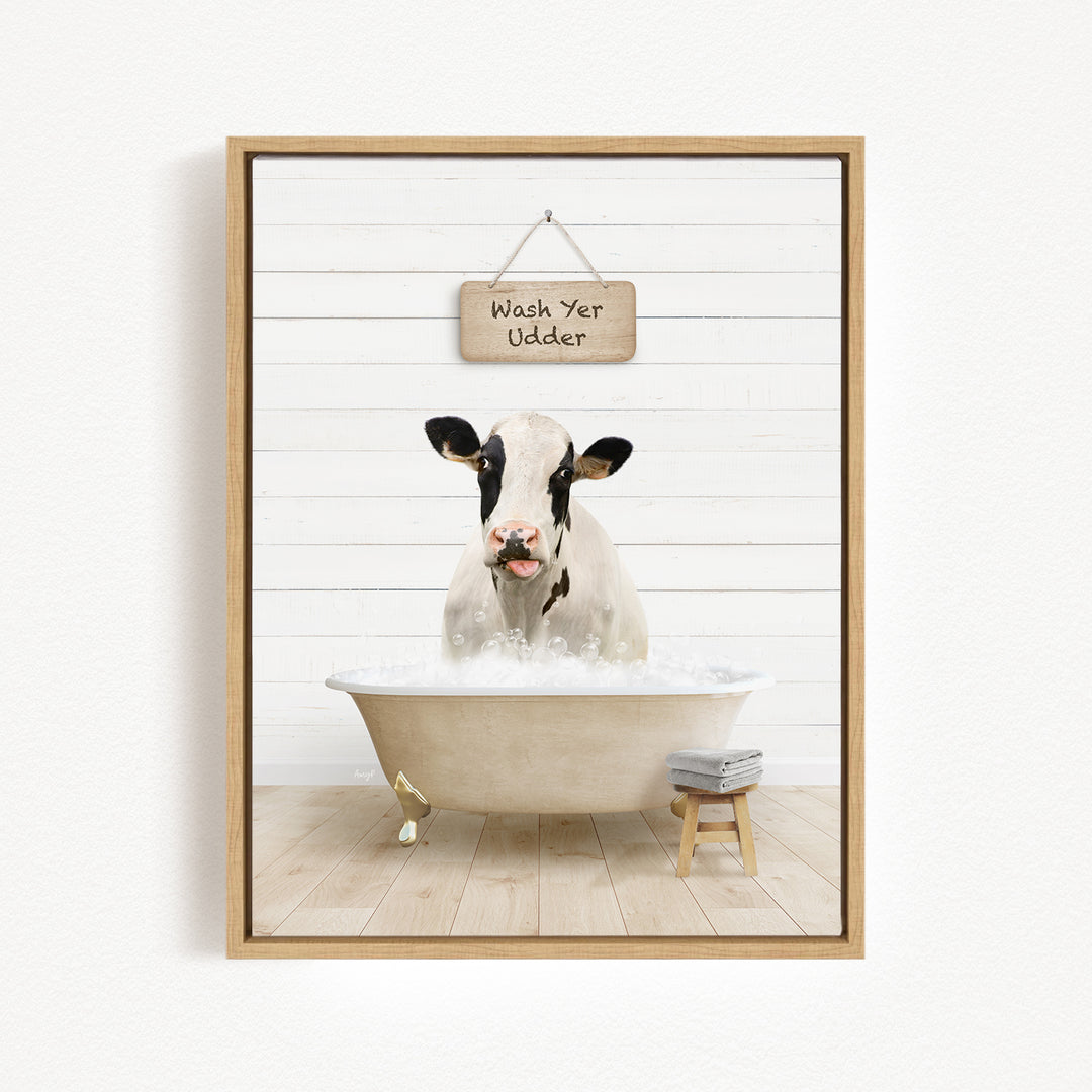 A black and white cow is sitting in a bathtub filled with water, with a sign above it that says "Wash Your Udders".