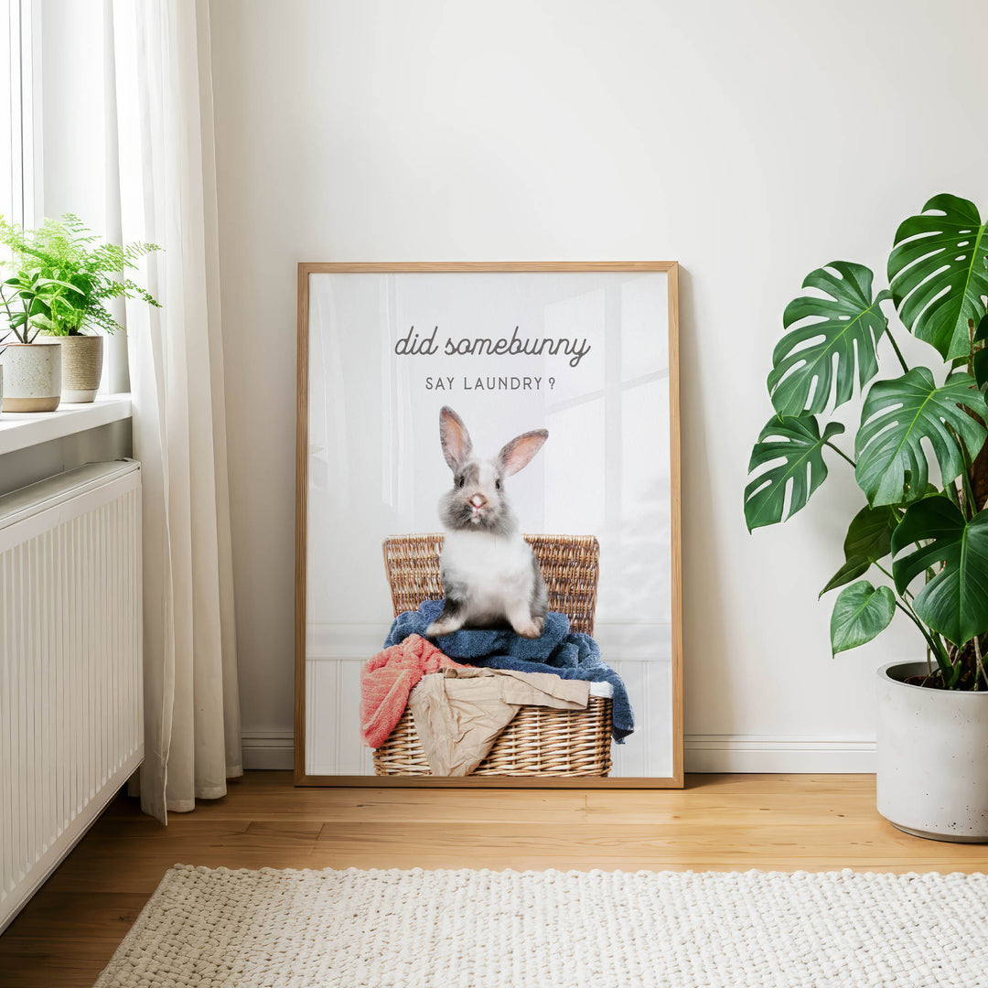 A framed poster featuring a rabbit sitting in a wicker basket, with the text "did some bunny say laundry" displayed above the image.
