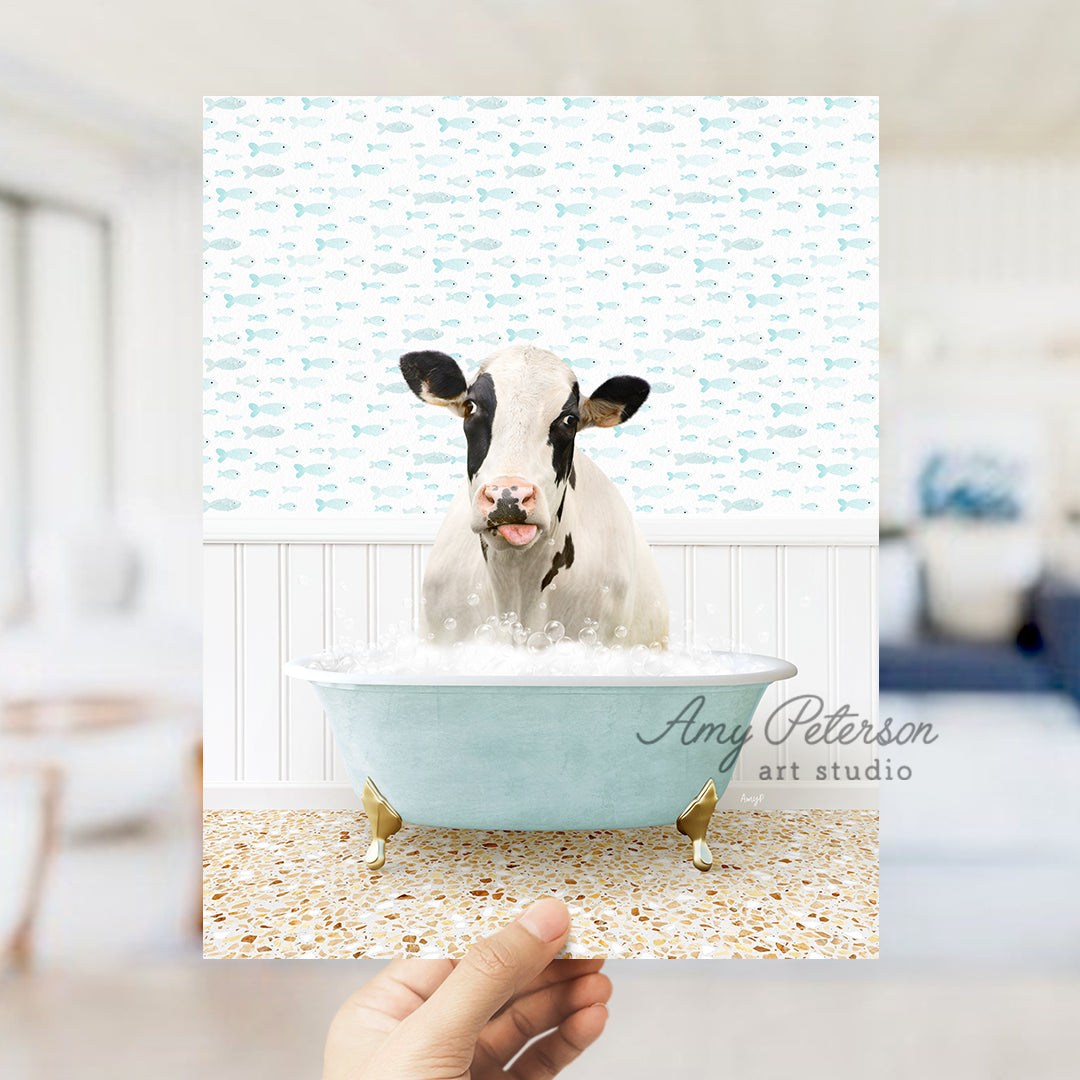 a hand holding up a picture of a cow in a bathtub