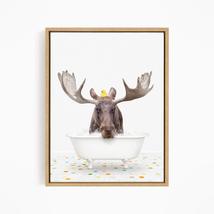 A moose with large antlers is sitting in a white bathtub, with a rubber duck perched on its head.