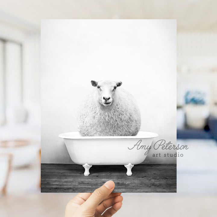 a hand holding a card with a sheep in a bathtub