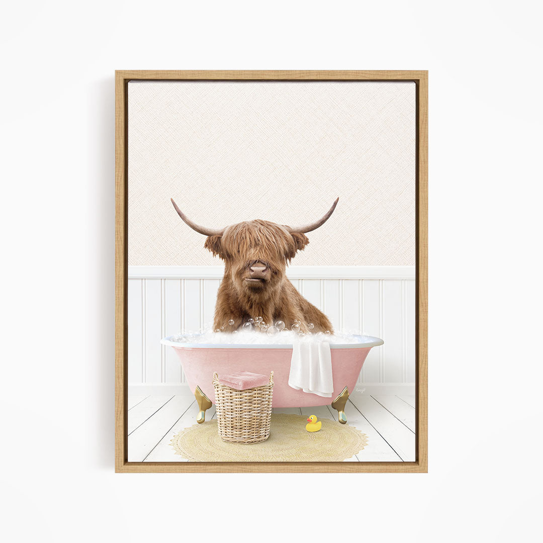 A brown cow with long horns is sitting in a pink bathtub filled with water, surrounded by a yellow rubber duck and a basket.