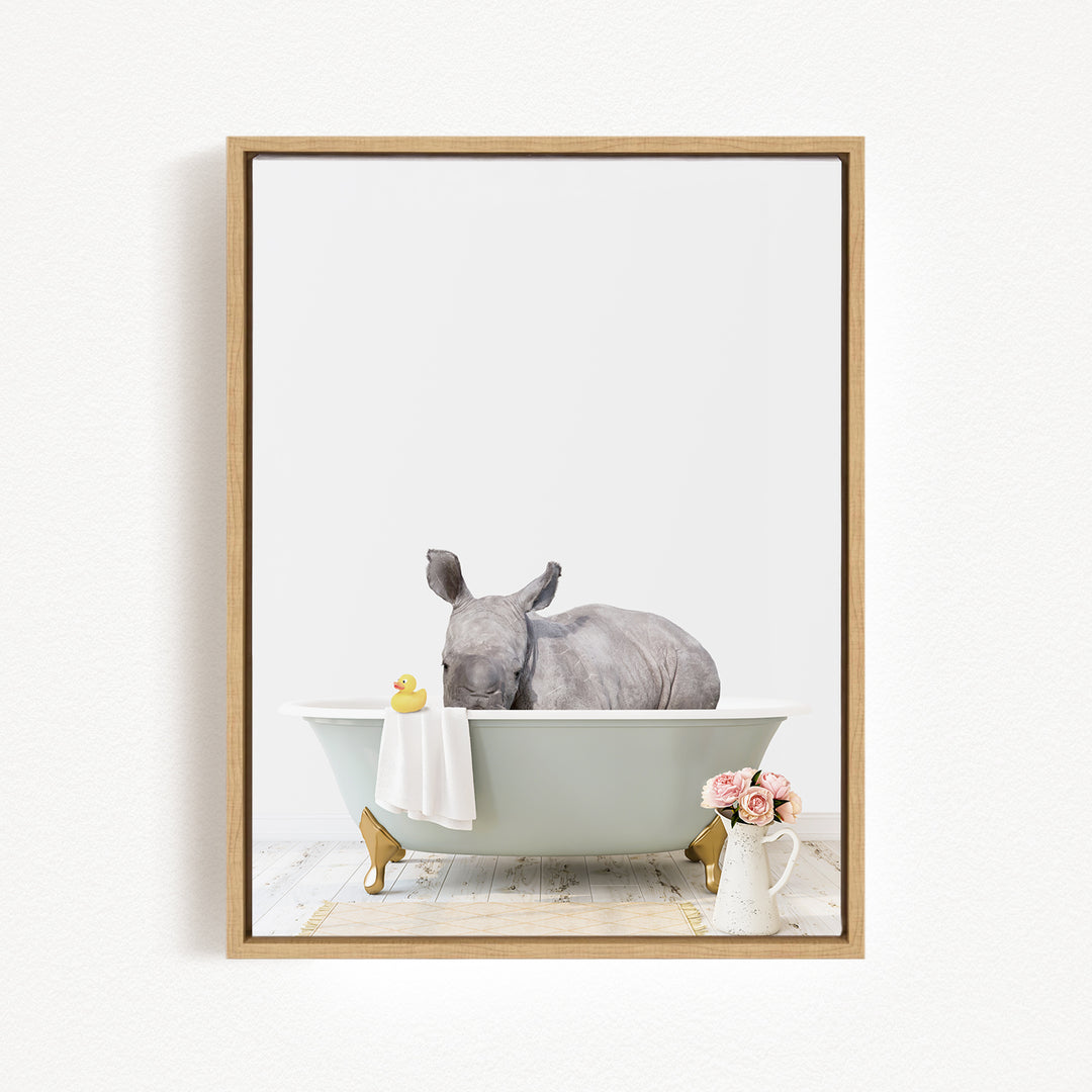 A rhinoceros is sitting in a bathtub filled with water, surrounded by a yellow rubber duck and a vase of pink flowers.