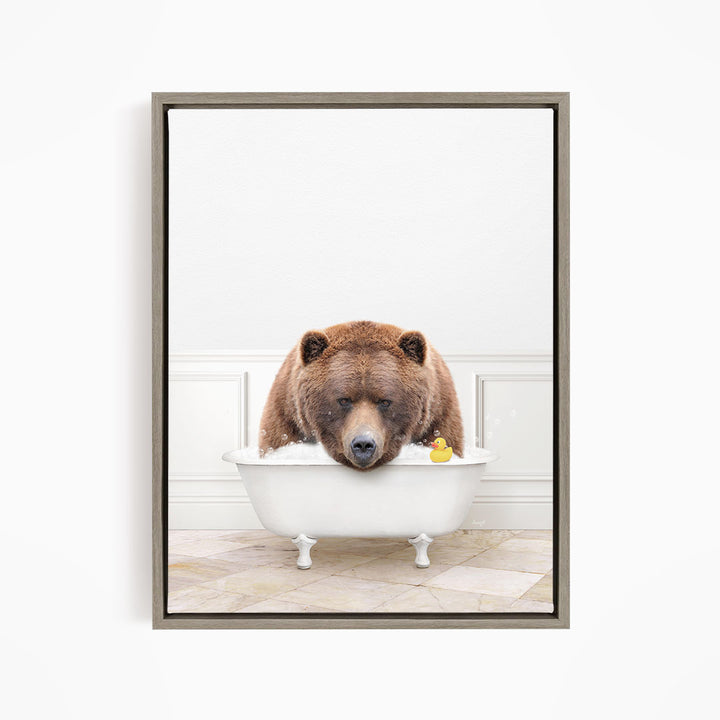 A brown bear is sitting in a white bathtub, with a yellow rubber duck floating in the water.