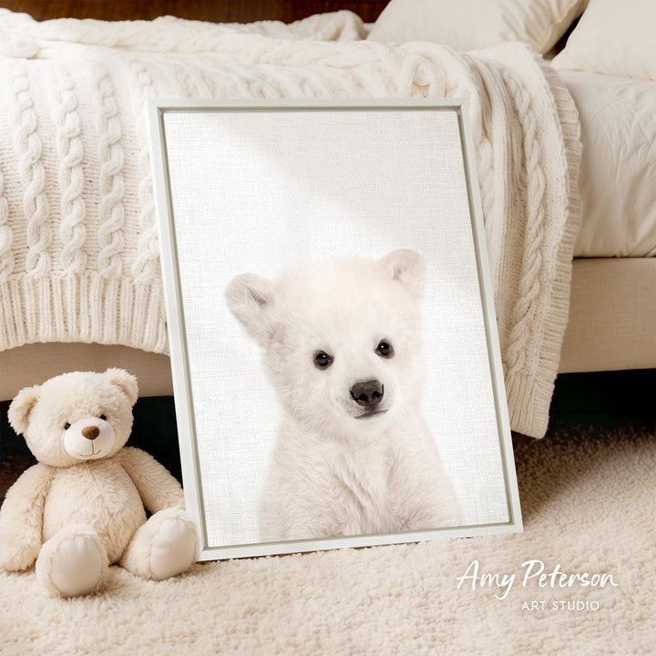 A framed photograph of a polar bear is displayed on a bed, accompanied by a teddy bear.