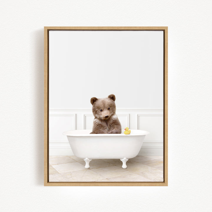 A brown bear sitting in a white bathtub, with a yellow rubber duck floating in the water.