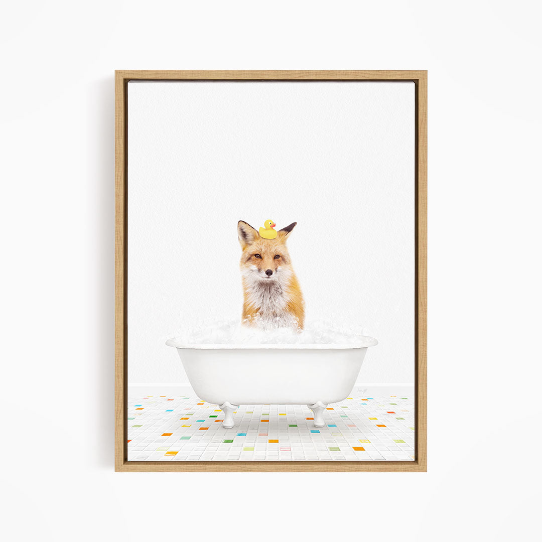 A fox is sitting in a white bathtub filled with bubbles, with a yellow rubber duck perched on its head.
