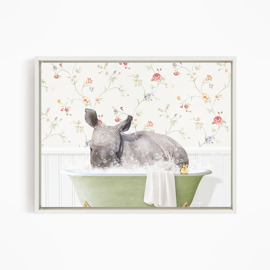 A rhinoceros is sitting in a green bathtub filled with water, surrounded by a floral wallpaper.