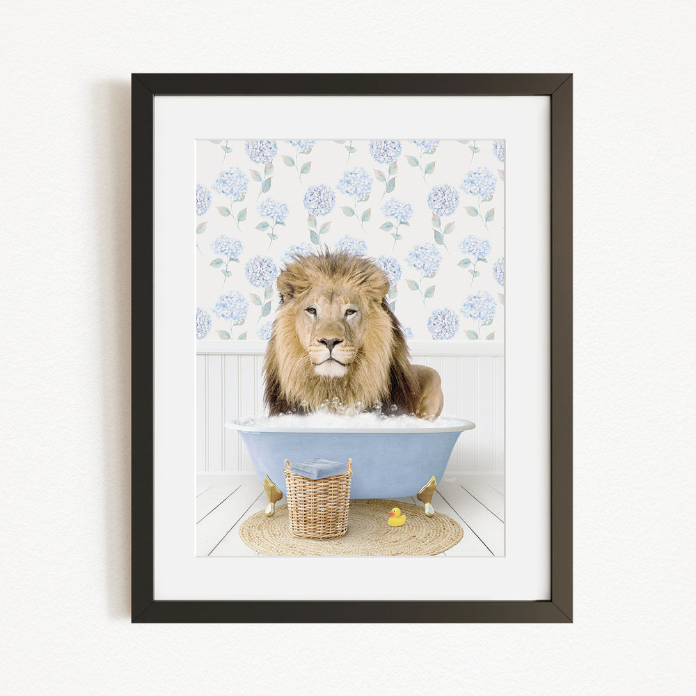 A lion is sitting in a blue bathtub filled with water, surrounded by a floral patterned wall and a basket of rubber ducks.