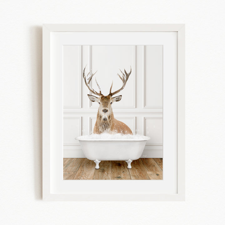 A deer with large antlers is sitting in a white bathtub filled with bubbles, creating a whimsical and unexpected scene.