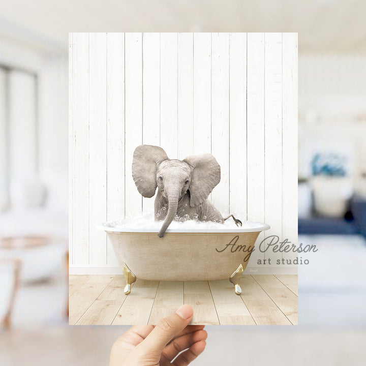 a hand holding up a picture of an elephant in a bathtub