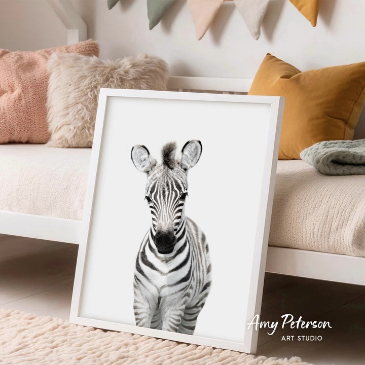 A framed black and white photograph of a zebra is displayed on a white wall in a cozy living room setting.