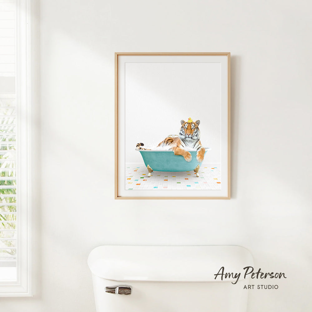 A framed print of a tiger sitting in a blue bathtub is hanging on a white wall.
