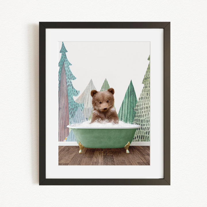 A small brown bear is sitting in a green bathtub, surrounded by a forest scene with trees and a snowy landscape.
