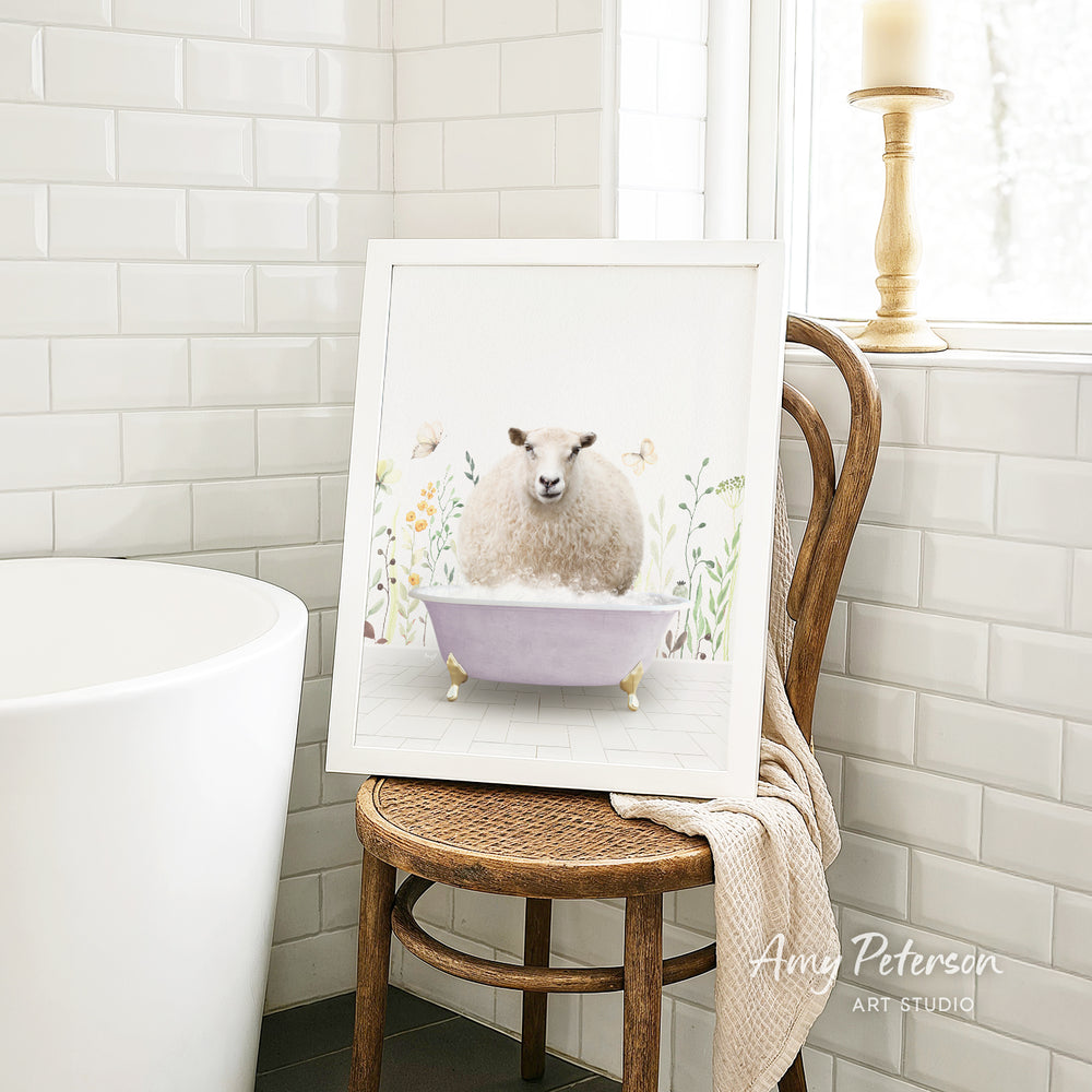 A framed illustration of a sheep sitting in a bathtub is displayed on a wooden chair in a bathroom setting.