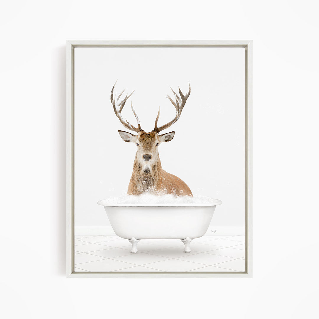 A deer with large antlers is sitting in a white bathtub filled with bubbles, creating a whimsical and unexpected scene.
