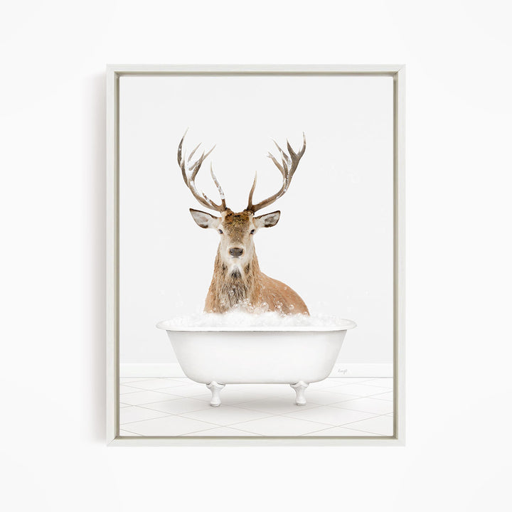 A deer with large antlers is sitting in a white bathtub filled with bubbles, creating a whimsical and unexpected scene.