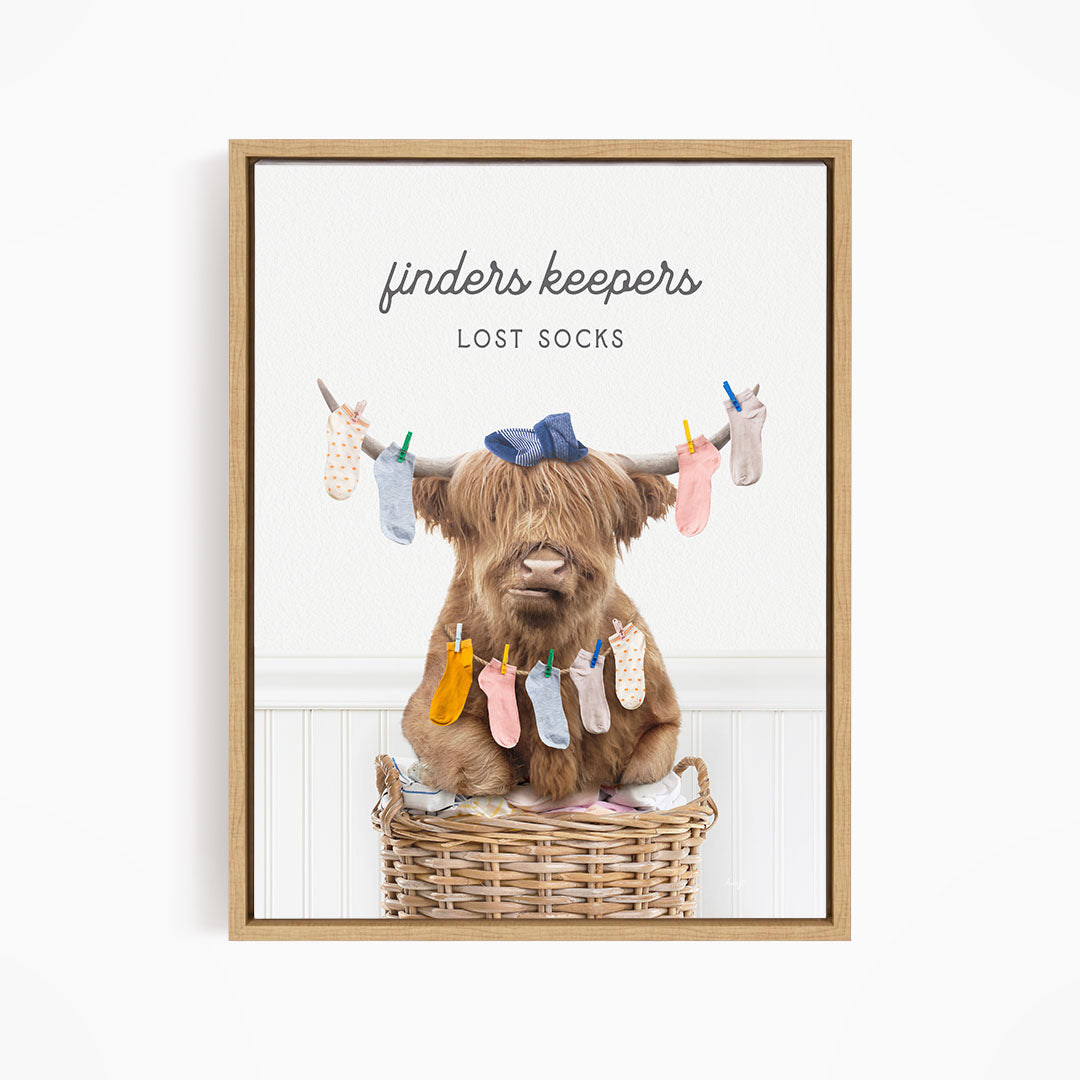A brown cow sitting in a wicker basket filled with colorful socks, with the text "finders keepers" and "lost socks" displayed above the image.
