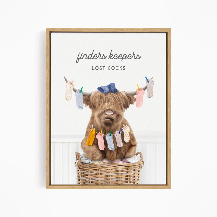 A brown cow sitting in a wicker basket filled with colorful socks, with the text "finders keepers" and "lost socks" displayed above the image.