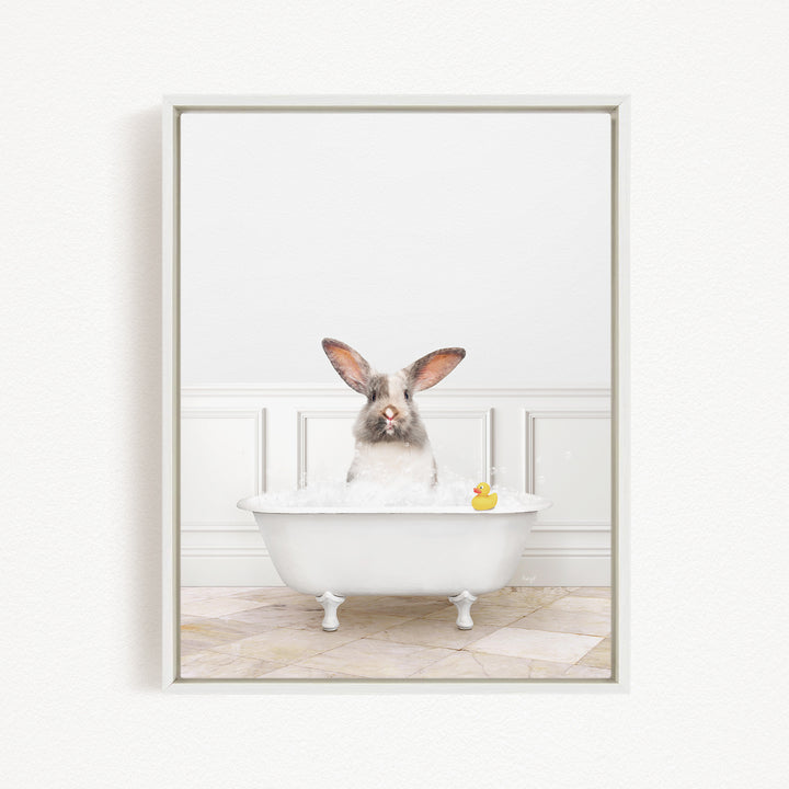 A white rabbit sitting in a white bathtub, with a rubber duck floating in the water.