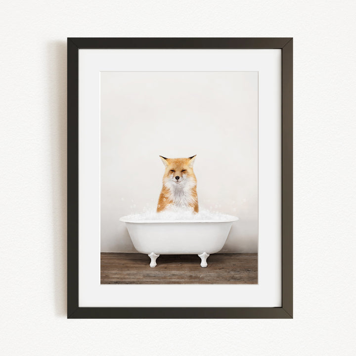A framed image of a fox sitting in a white bathtub filled with bubbles.