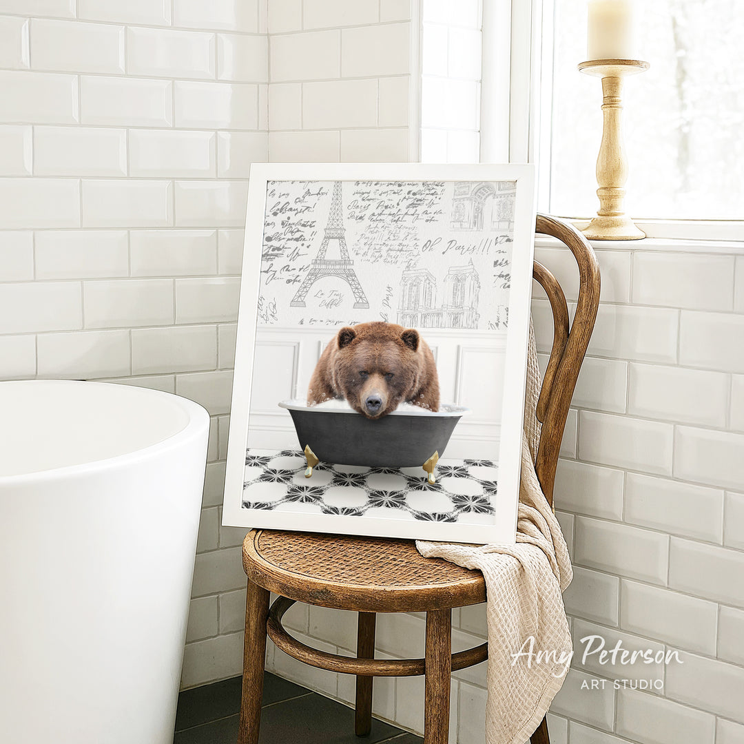 A framed image of a bear sitting in a bathtub, with a tiled wall and a window in the background.