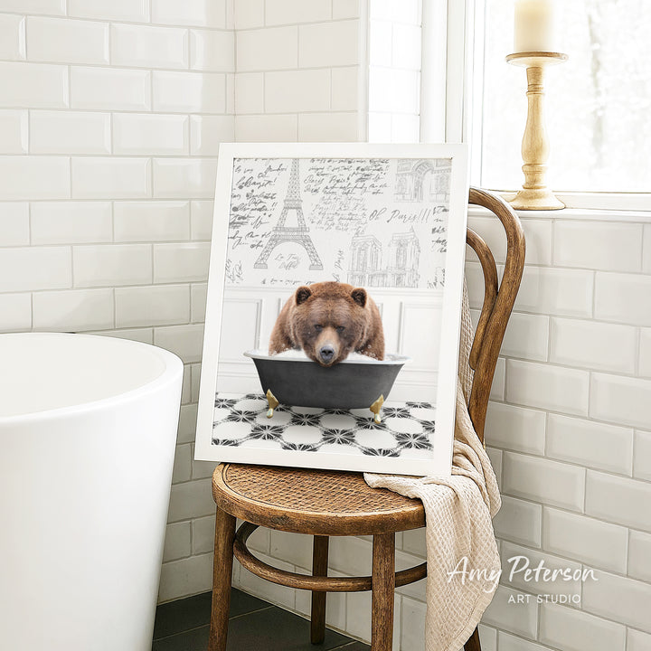 A framed image of a bear sitting in a bathtub, with a tiled wall and a window in the background.