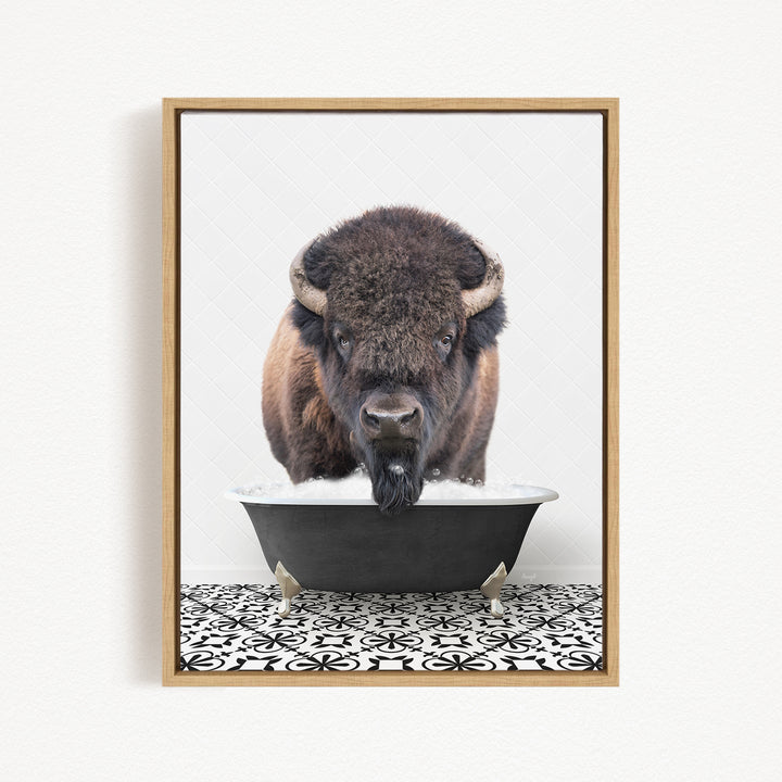 A buffalo with a long beard is standing in a black tub filled with water, looking directly at the camera.