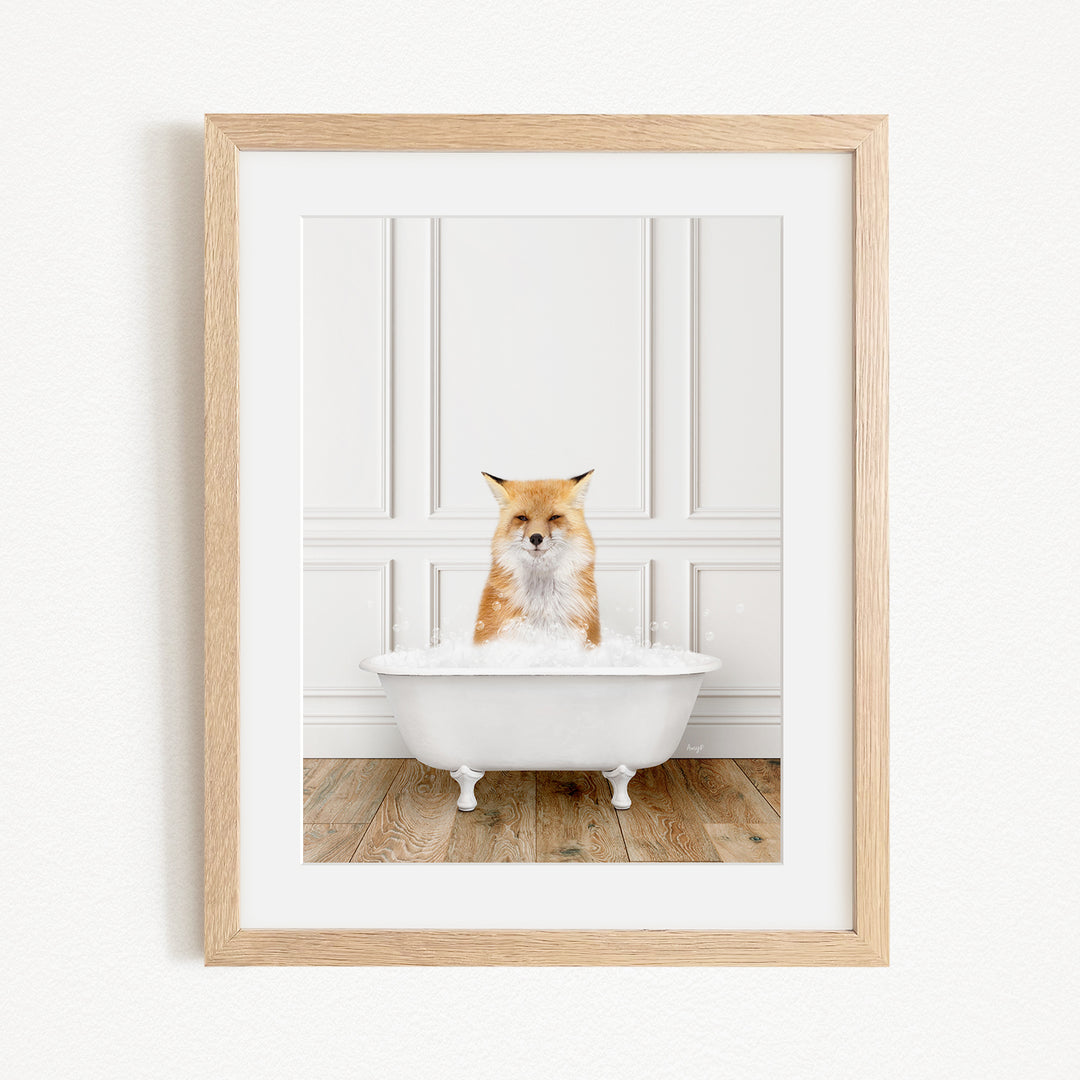 A red fox is sitting in a white bathtub filled with bubbles, looking directly at the camera.