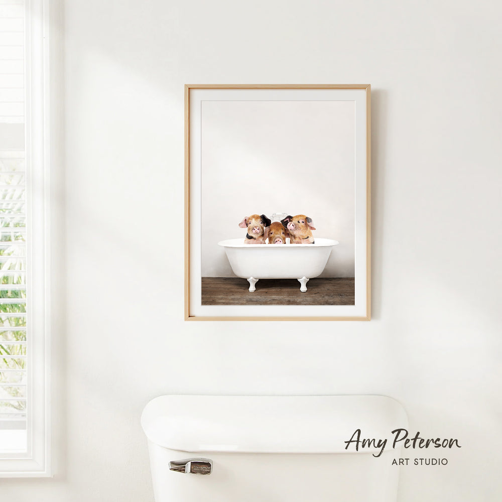 A framed image of three small brown and white dogs sitting in a white bathtub, with a window and a white toilet visible in the background.