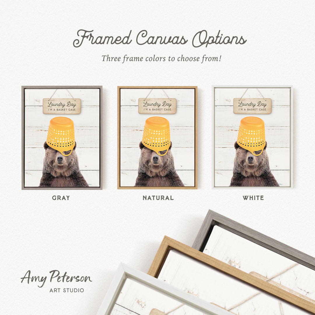 three framed canvas options featuring a bear wearing a yellow bucket hat. The bear is positioned in front of a sign that reads "Laundry Day I'm a basket case". The options include a gray, natural, and white frame.