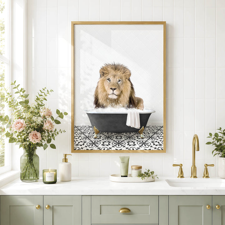 A framed image of a lion sitting in a bathtub, surrounded by flowers and candles, is displayed on a white tiled wall above a bathroom sink.