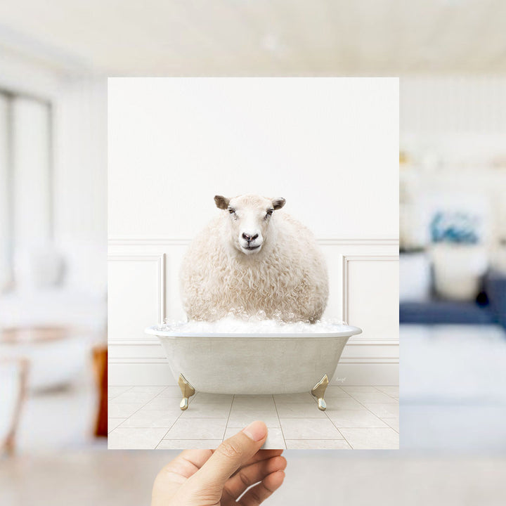 A fluffy white sheep sitting in a white bathtub filled with bubbles, with a blurred background suggesting a bathroom setting.