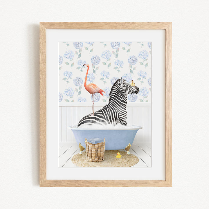 A framed illustration depicting a zebra sitting in a bathtub, with a flamingo standing on its back and a basket of rubber ducks nearby.
