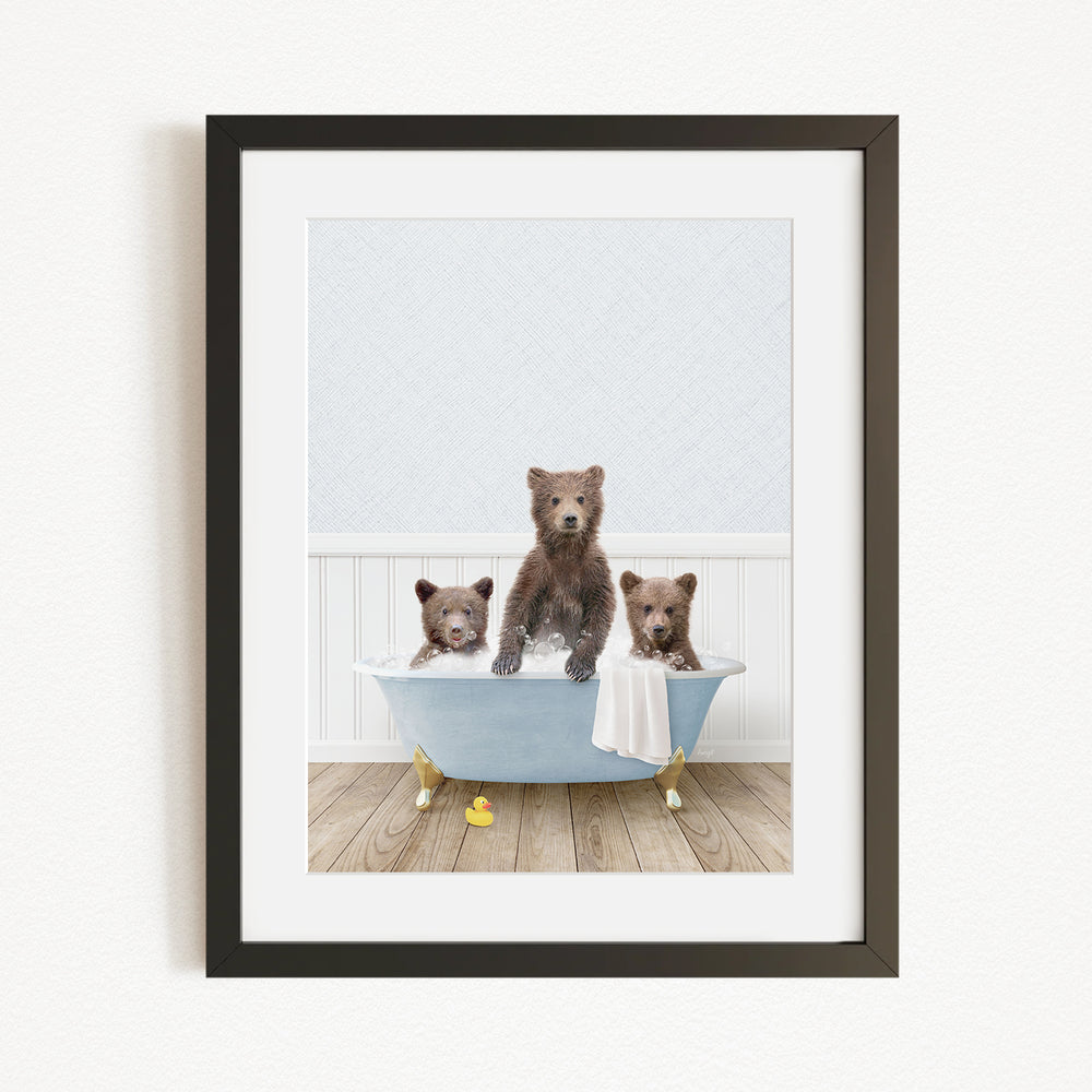 A framed image depicting three brown bears sitting in a blue bathtub, with one bear sitting on the edge of the tub and the other two bears sitting inside the tub.