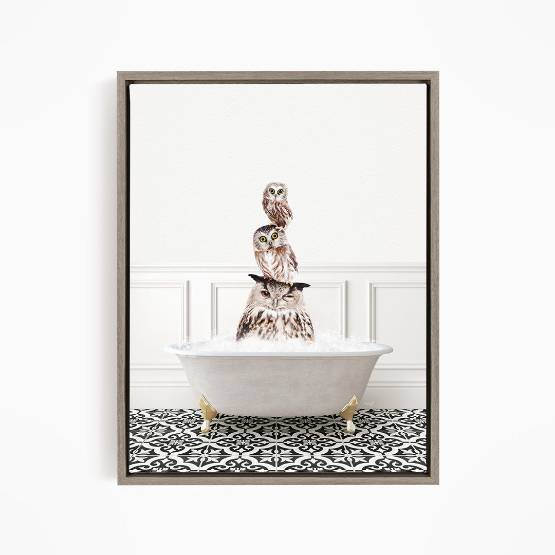 A framed image depicting a group of owls sitting in a bathtub, with one owl perched on top of the others.