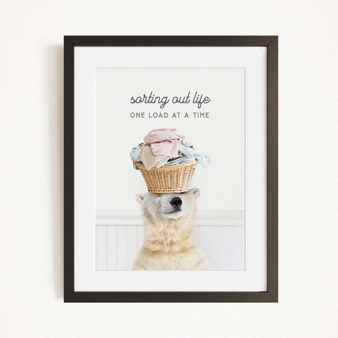 A polar bear balancing a basket of laundry on its head, with the text "sorting out life" above the basket.