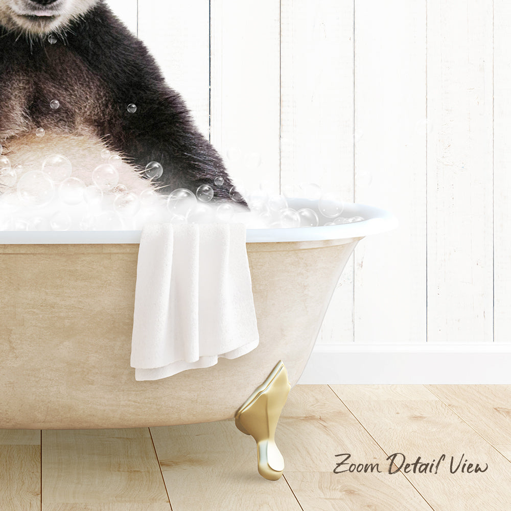 A panda sitting in a bathtub filled with bubbles, with a towel and gold bathtub leg visible.