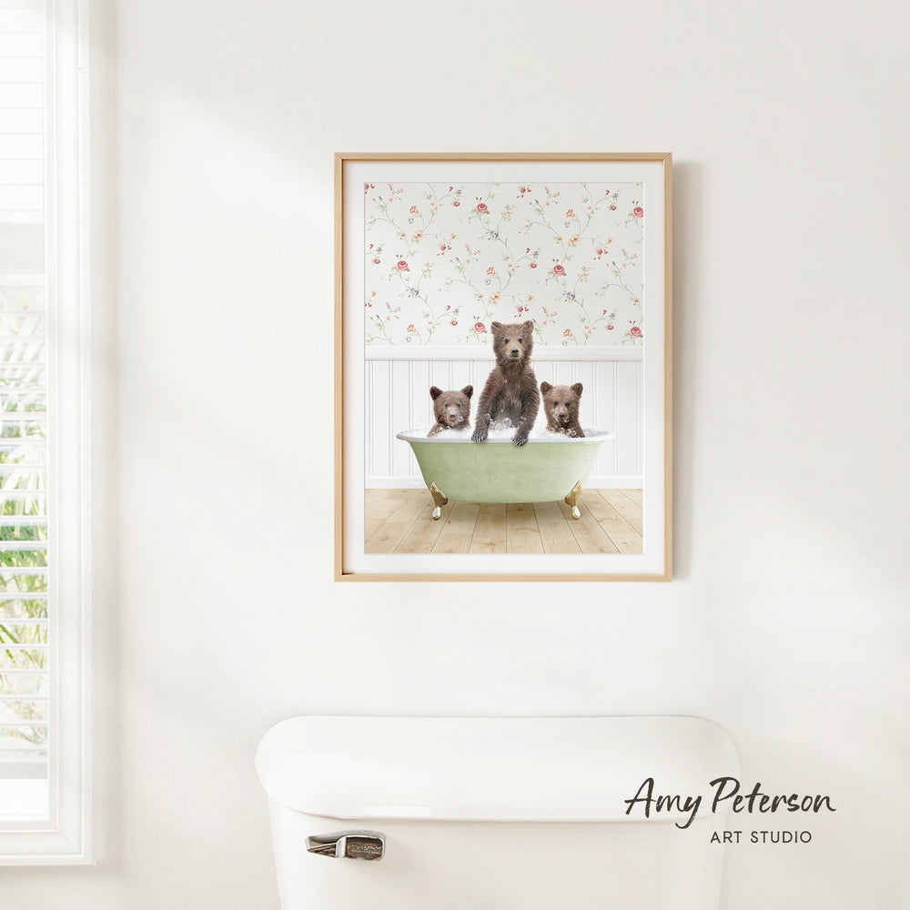 A framed image of three bears sitting in a bathtub, with a floral pattern on the wall behind them.