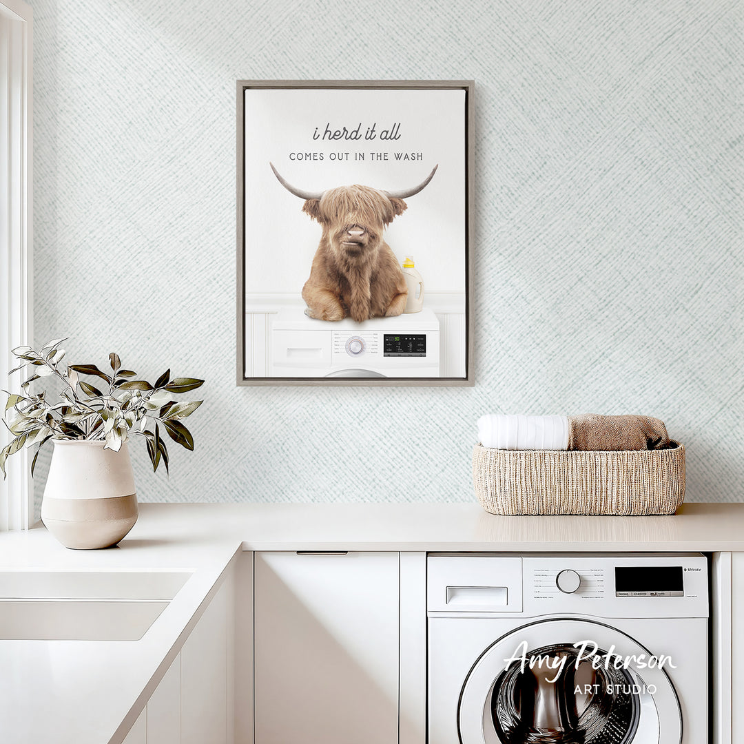 a framed poster of a Highland cow sitting on a washing machine, with the caption "I herd it all comes out in the wash".
