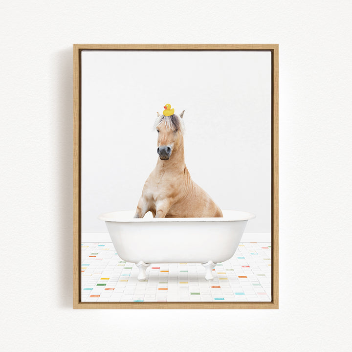 A light brown horse is sitting in a white bathtub, with a yellow rubber duck perched on its head.