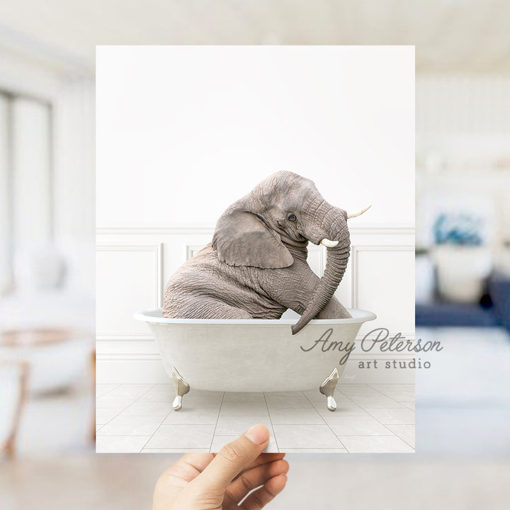 a person holding up a picture of an elephant in a bathtub